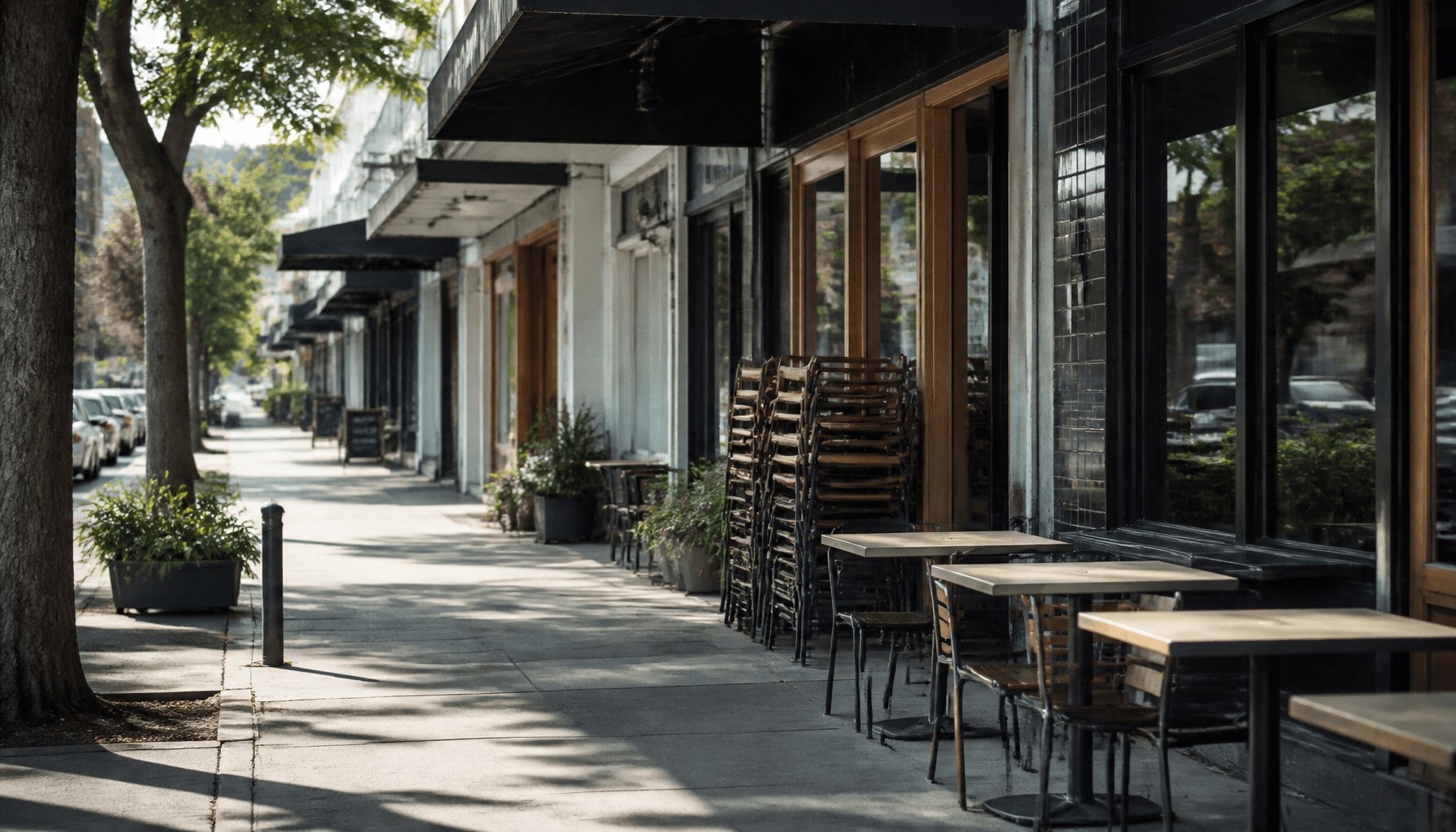 Quiet NZ café strip with empty outdoor tables outside independent hospitality premises