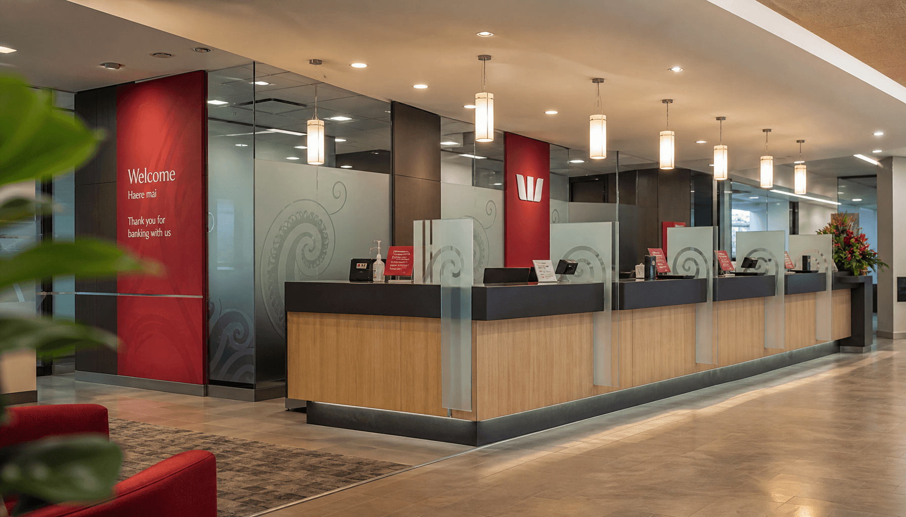Interior of a New Zealand retail bank branch with a modern service counter and koru-motif frosted glass panels