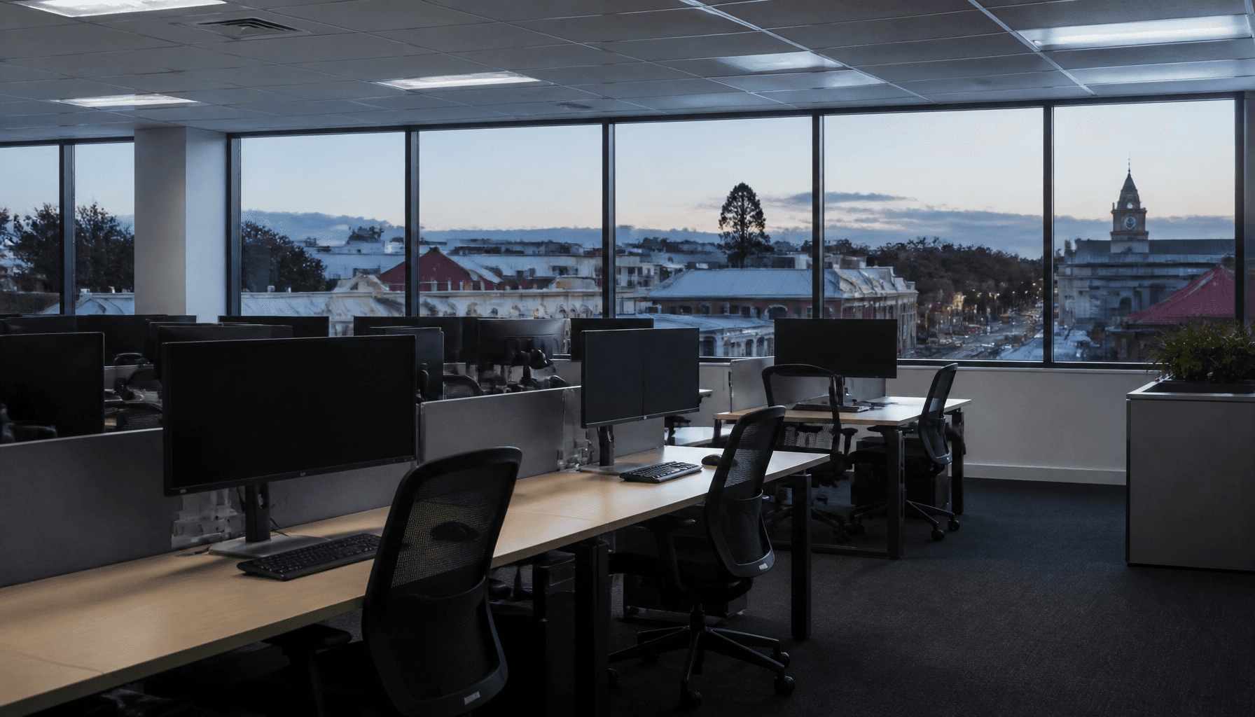 Empty open-plan office desks in a provincial New Zealand city at dusk