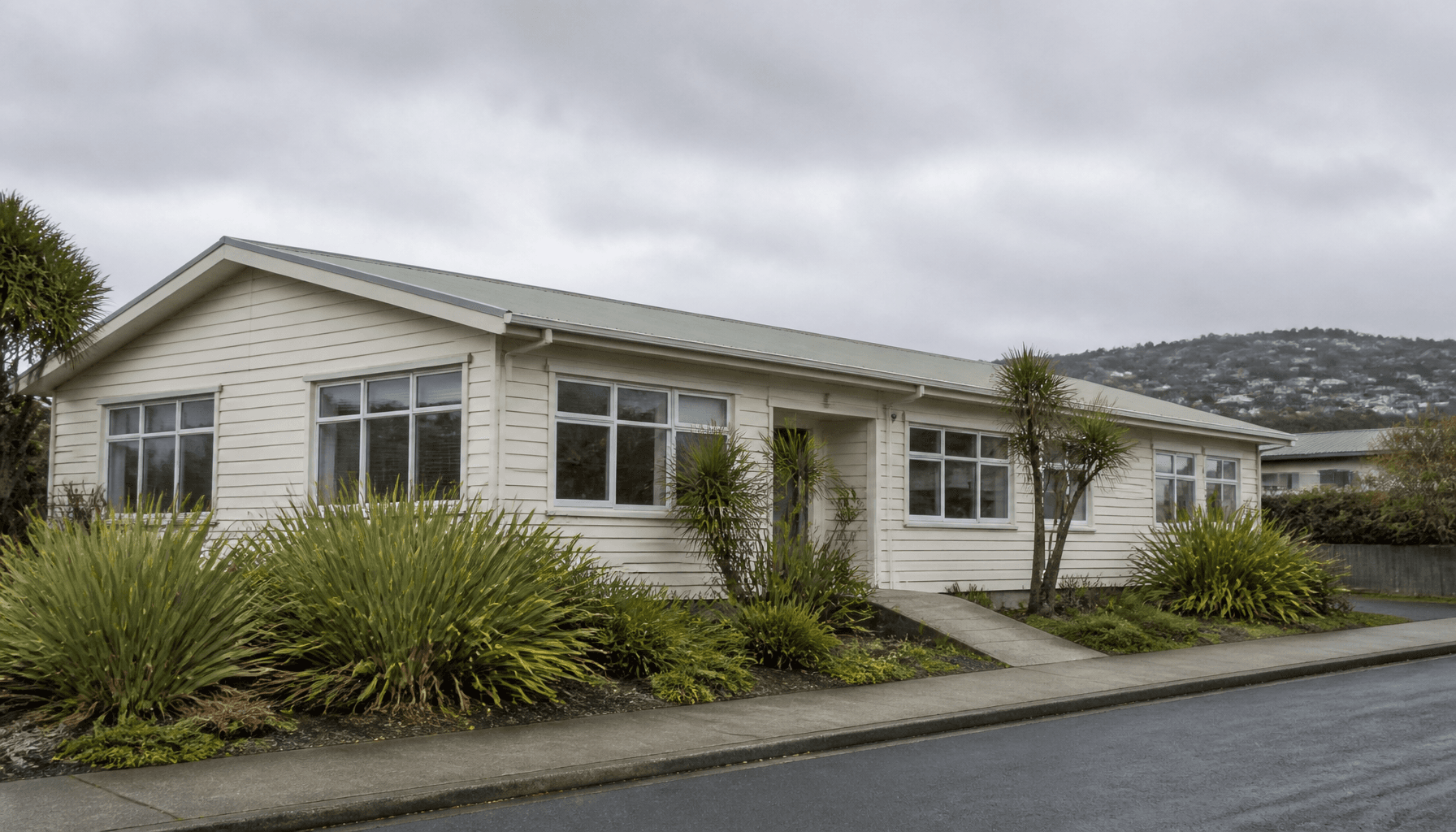 A quiet Wellington suburban community services office building surrounded by native flax plantings on an overcast morning