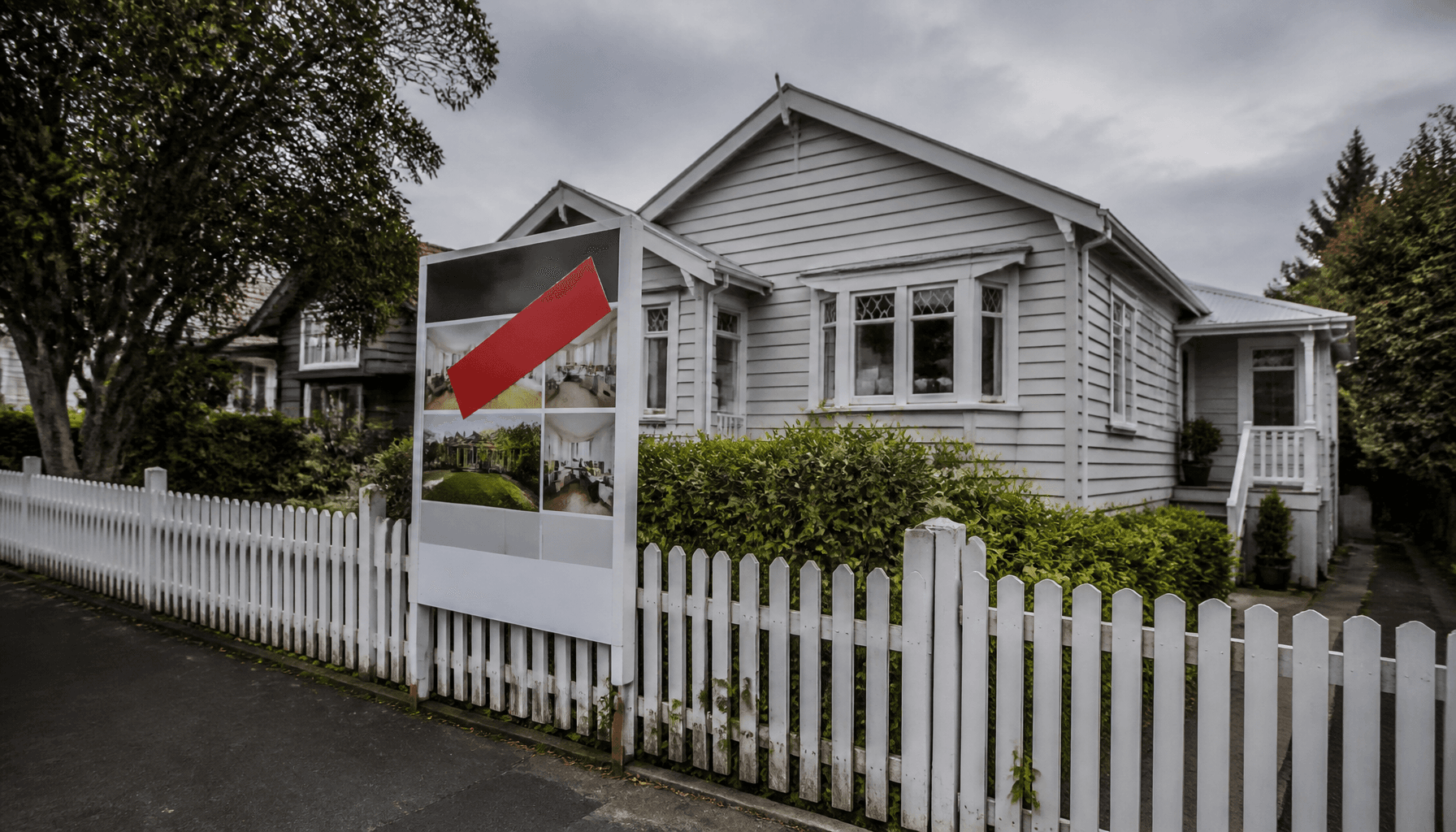 Suburban Auckland house with a real estate sale board at the front fence