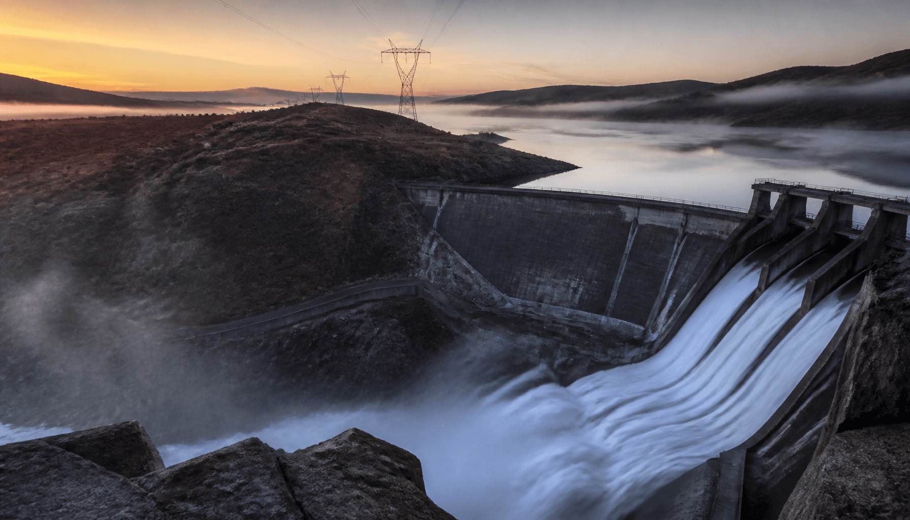 New Zealand hydro reservoir and dam with transmission lines at dawn