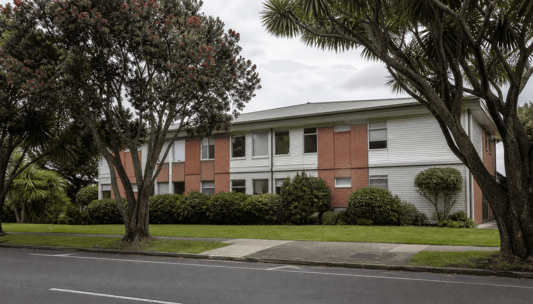 Anonymous two-storey commercial office building on a quiet Hamilton, New Zealand street under overcast morning light